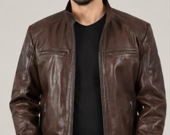 May include: A dark brown leather jacket featuring a stand-up collar, a full-length front zip, and two horizontal zipped chest pockets. The jacket has long sleeves with zipped cuffs and is worn over a plain black t-shirt and dark trousers.