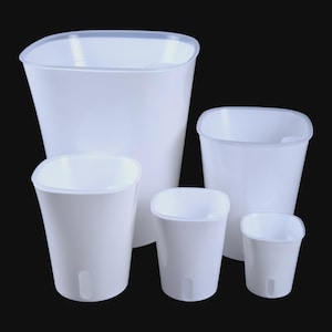 May include: A collection of five white plastic plant pots of varying sizes. Each pot has a square top with rounded corners and a slightly tapered body. The pots are designed for indoor or outdoor use and are set against a black background.