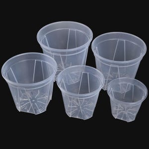 Può includere: Cinque vasi di plastica trasparente di varie dimensioni sono disposti su uno sfondo nero. I vasi hanno una forma cilindrica con nervature di supporto verticali e fori di drenaggio sul fondo. Sono progettati per la semina.