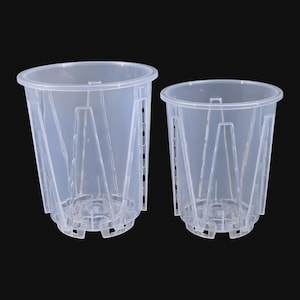 Könnte beinhalten: Zwei transparente Pflanztöpfe aus Kunststoff in verschiedenen Größen. Die Töpfe haben eine zylindrische Form mit leicht ausgestelltem Rand und einer Reihe von vertikalen Stützen im Inneren. Für Drainage und Belüftung konzipiert.