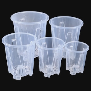 Könnte beinhalten: Fünf transparente Orchideentöpfe aus Kunststoff in verschiedenen Größen. Jeder Topf hat eine zylindrische Form mit ausgestelltem Rand, vertikalen Stützen und Drainagelöchern. Sie sind für optimale Luftzirkulation und gesunde Wurzeln konzipiert.