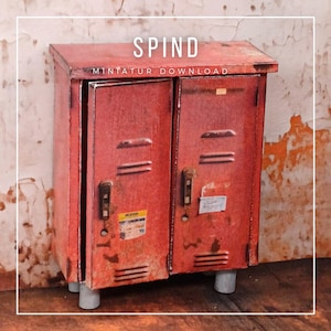 Könnte beinhalten: Ein kleiner, roter Metallschrank mit zwei Türen, der Gebrauchsspuren aufweist. Das Wort "SPIND" ist oben aufgedruckt, darunter "MINTATUR DOWNLOAD". Der Schrank hat ein verwittertes Aussehen, mit kleinen Etiketten und grauen zylindrischen Füßen.