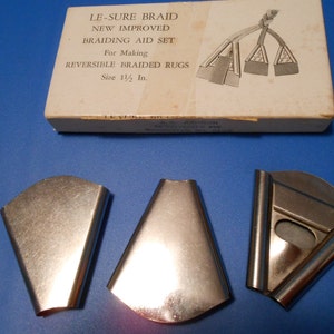 May include: A set of three silver braiding tools for making reversible braided rugs. The tools are in a box that says "Le-Sure Braid New Improved Braiding Aid Set For Making Reversible Braided Rugs Size 1 1/2 In."