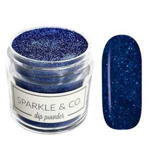 May include: A clear jar filled with sparkling navy blue dip powder, with a matching nail swatch. The jar has a label that reads "SPARKLE & CO. dip powder". The nail swatch is an oval shape with a vertical line.