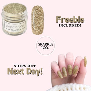 May include: A jar of gold glitter dip powder with the text "SPARKLE & CO. dip powder" on the label. A small sample of the glitter is shown next to the jar. The text "Freebie INCLUDED!" is shown in the upper right corner of the image. A hand with gold glitter nails is shown in the lower right corner of the image. The text "SHIPS OUT Next Day!" is shown in the lower left corner of the image.