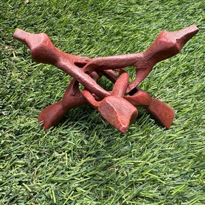 Puede incluir: Un soporte de madera rojo con tres patas, diseñado para sostener cristales u otros objetos. El soporte está hecho de una sola pieza de madera tallada de forma intrincada.