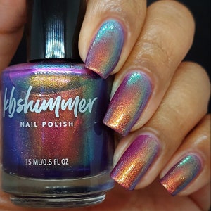 May include: A bottle of KBShimmer nail polish with a holographic finish. The bottle is labeled "KBShimmer Nail Polish" and "15 ML/0.5 FL OZ". The polish is a multi-colored iridescent shimmer.