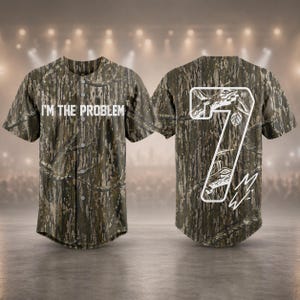 May include: Camouflage baseball jersey with the text "I'M THE PROBLEM" on the front. The back features a white number 7 with a nature-themed design and a signature. The jersey has a button-up front and short sleeves.