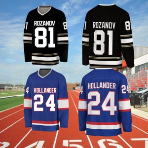 May include: Four long-sleeved hockey jerseys. Two black jerseys with white and gold stripes, the name "ROZANOV" and the number "81". Two blue jerseys with white and red stripes, the name "HOLLANDER" and the number "24".