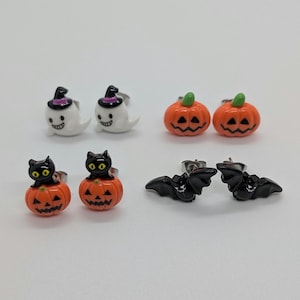 Peut inclure: Une collection de boucles d'oreilles à clous sur le thème d'Halloween. Les boucles d'oreilles présentent des motifs de fantômes avec des chapeaux de sorcière, de citrouilles oranges, de chats noirs sur des citrouilles et de chauves-souris noires.
