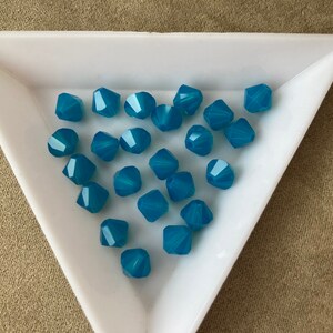 May include: A white triangular dish filled with teal blue faceted glass beads.