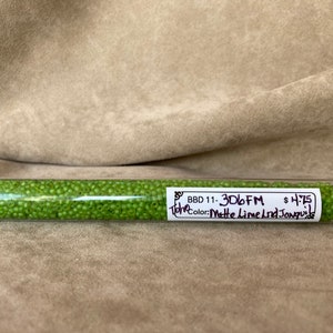 May include: A clear plastic tube filled with small, matte lime green seed beads. The tube has a white label with black text that reads "BBD 11- 3D6FM" and "Matte Lime Lnd Jonquil". The beads are a vibrant green color.