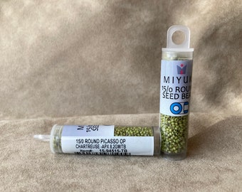 May include: Two small clear plastic tubes filled with green seed beads. The tubes have labels that read "MIYUKI 15/0 ROUND SEED BEADS" and "15/0 ROUND PICASSO OP CHARTREUSE - APX 8.2GM/TB Item#: 15-94515-TB".