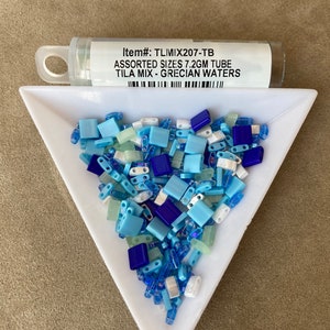 May include: A small tube of assorted blue, white, and green glass tile beads. The tube is labeled "Item#: TLIMIX207-TB ASSORTED SIZES 7.2GM TUBE TILA MIX - GRECIAN WATERS".