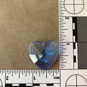 May include: A light blue crystal heart charm with a faceted design. The charm is approximately 1 inch in size.