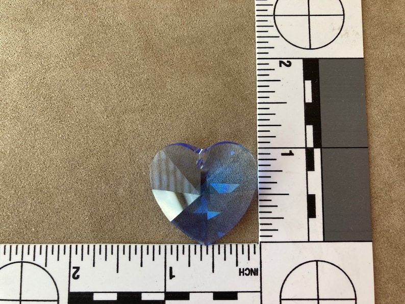 May include: A light blue crystal heart charm with a faceted design. The charm is approximately 1 inch in size.