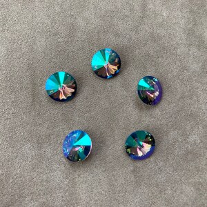 May include: Five iridescent blue round rhinestones with a faceted design.