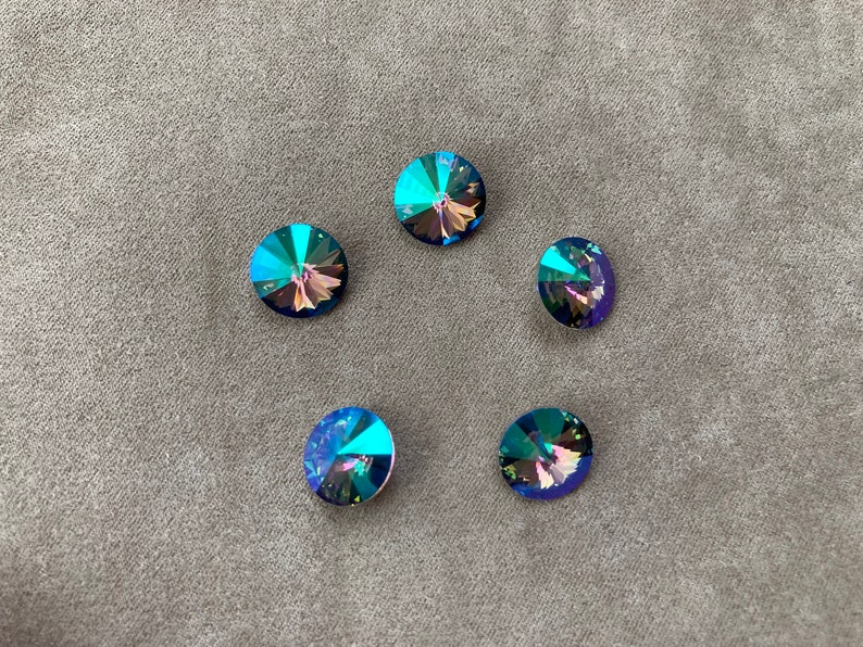 May include: Five iridescent blue round rhinestones with a faceted design.