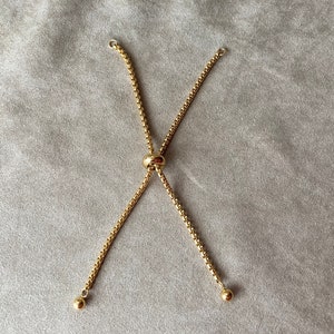May include: A gold chain bracelet with a sliding clasp. The chain is made of small, linked circles.