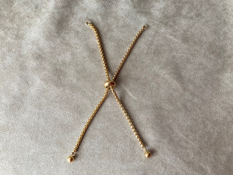 May include: A gold chain bracelet with a sliding clasp. The chain is made of small, linked circles.