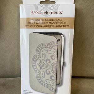 May include: A rectangular white product box for a Basic Elements magnetic needle case. The packaging features a beige and grey mandala-style pattern on the front, with the text "BASIC elements" and "MAGNETIC NEEDLE CASE" printed clearly.