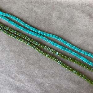 May include: Three strands of square beads, two strands are turquoise blue and one strand is green.