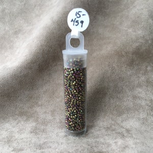 May include: A small clear plastic tube filled with iridescent brown seed beads. A white label with the number "15-459" is attached to the top of the tube.