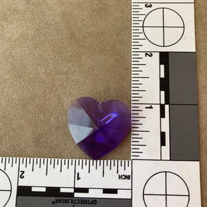 May include: A purple heart-shaped crystal prism with facets. The prism is approximately 1 inch in size.