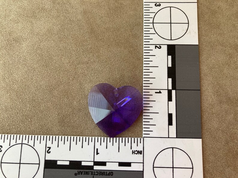 May include: A purple heart-shaped crystal prism with facets. The prism is approximately 1 inch in size.