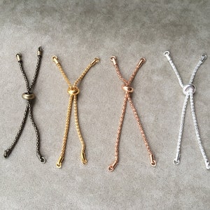 May include: Four different colored cord stoppers with a metal ring. The cords are silver, gold, rose gold, and black.