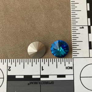 Peut inclure: Deux strass ronds et facet&eacute;s. L'un est argent&eacute; et l'autre est bleu vif. Les strass sont &agrave; c&ocirc;t&eacute; d'une r&egrave;gle avec des marques en pouces.