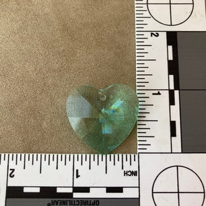 May include: A light green heart-shaped crystal prism with a hole at the top for hanging.