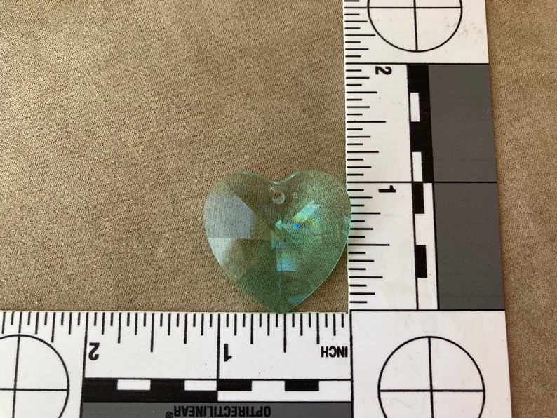 May include: A light green heart-shaped crystal prism with a hole at the top for hanging.
