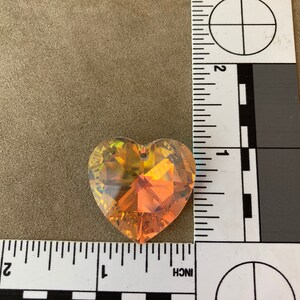 May include: A heart-shaped crystal prism with a gold and orange iridescent finish. The prism is approximately 1 inch in size.
