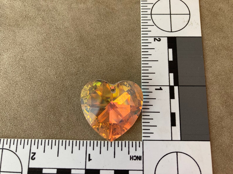 May include: A heart-shaped crystal prism with a gold and orange iridescent finish. The prism is approximately 1 inch in size.