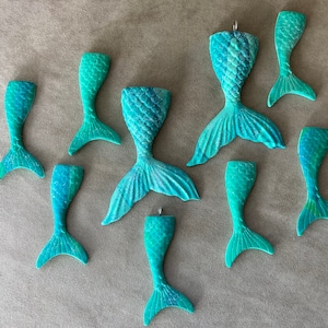 May include: Ten teal blue mermaid tail ornaments with a variety of designs and sizes. The ornaments are made of a smooth, hard plastic.