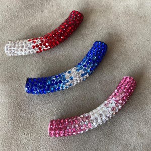 May include: Three curved, jeweled hair clips in red, white, and blue, white, and pink, white, and blue.