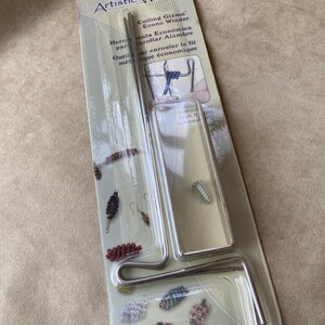 May include: An Artistic Wire Coiling Gizmo Econo Winder tool in original packaging. The set includes a silver metal U-bracket, two crank rods, and one screw. The packaging features product text, illustrations of coiled wire designs, and instructions.