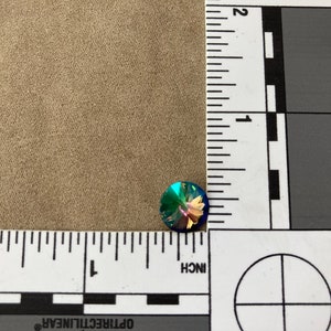 May include: A single iridescent blue, green, and purple round rhinestone with a faceted surface.