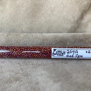 May include: A clear plastic tube filled with small, red iridescent seed beads. The label on the tube reads "BBD 11-254A, Matsuno Color: Red Iris, £4.50".