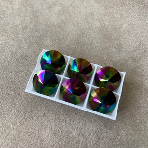 May include: Six iridescent round glass rhinestones in a white plastic tray. The rhinestones have a rainbow effect with shades of green, blue, purple, and gold.