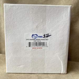 May include: A white rectangular box containing a 5-piece shaping wood punch set. A label on the front displays the Eurotool logo, the text 5 PC SHAPING WOOD PUNCH SET, the model number DAP-140.05, a barcode, and the text MADE IN INDIA.