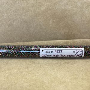 Op de afbeelding: Een transparante buis gevuld met kleine, iriserende kralen. De kralen vertonen een mix van kleuren, waaronder groen, paars en brons. De buis heeft een wit etiket met de tekst "BBD 11-455 D" en "Color: Met. Variegated Iris!"