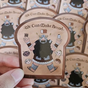 Pode incluir: Um adesivo marrom e bege com uma ilustração de desenho animado de uma pessoa barbuda vestindo uma túnica marrom e segurando um pão. O adesivo diz "We Can Make Bread." Há personagens de desenho animado menores ao redor do personagem principal.
