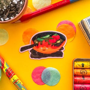 May include: A vibrant yellow background features a cactus in a small pot, colored pencils, and a sticker of a cartoon character cooking food in a pan. Colorful round confetti and a small box are also visible.