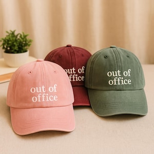 May include: Three baseball caps in different colors: pink, burgundy, and green. Each cap has the text "out of office" embroidered in white on the front.