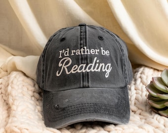 May include: A black distressed baseball cap with the text "I'd rather be Reading" embroidered in white.
