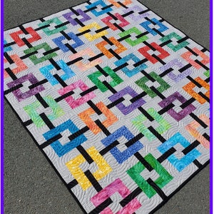 May include: A colourful quilt with a geometric design featuring interlocking squares in various colours, including red, blue, green, and yellow, connected by black lines. The quilt is labelled "Connections" and the brand is "Wild Daisy Quilts".