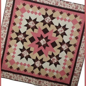 May include: A quilt with a star pattern in shades of pink, brown, and beige. The quilt is surrounded by a border of floral fabric. The text "Wild Daisy Quilts" and "Dressed to the Nines" is printed below the quilt.