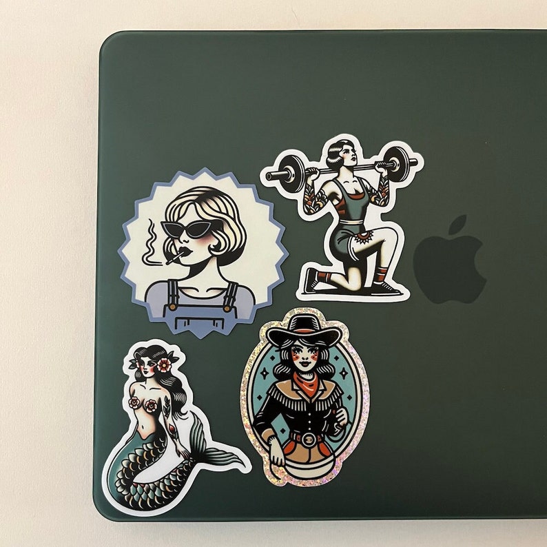 May include: Four vintage-style stickers featuring women in different poses. One sticker shows a woman with a cigarette in her mouth and sunglasses, another shows a woman lifting weights, another shows a woman with a cowboy hat, and the last shows a mermaid.